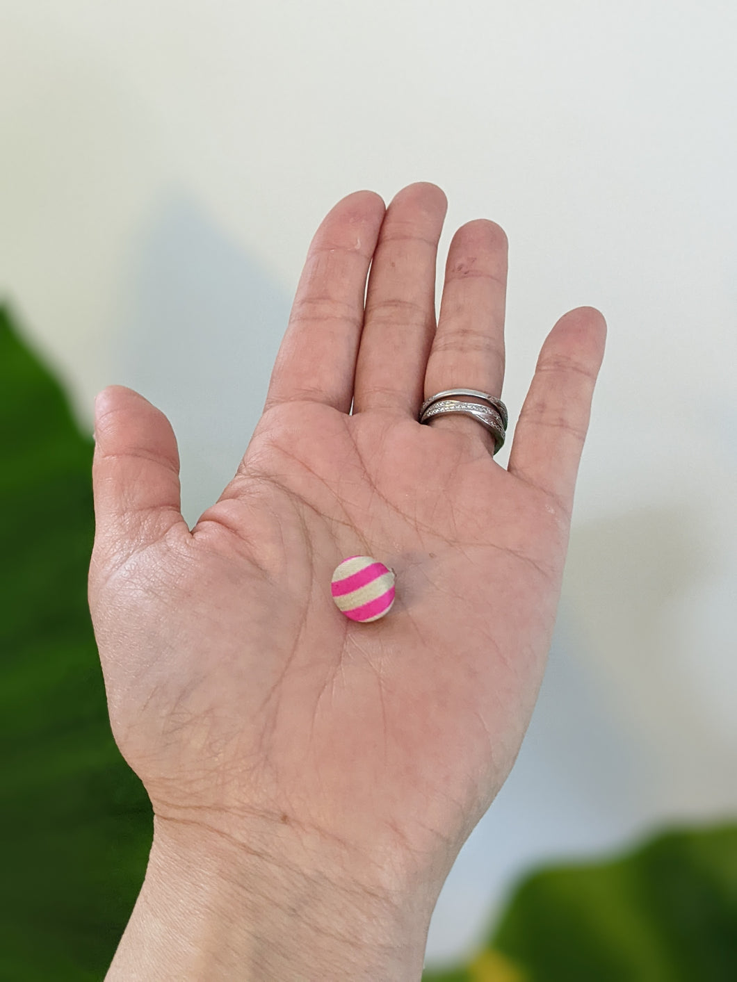 silk earring with pink and white stripe on palm