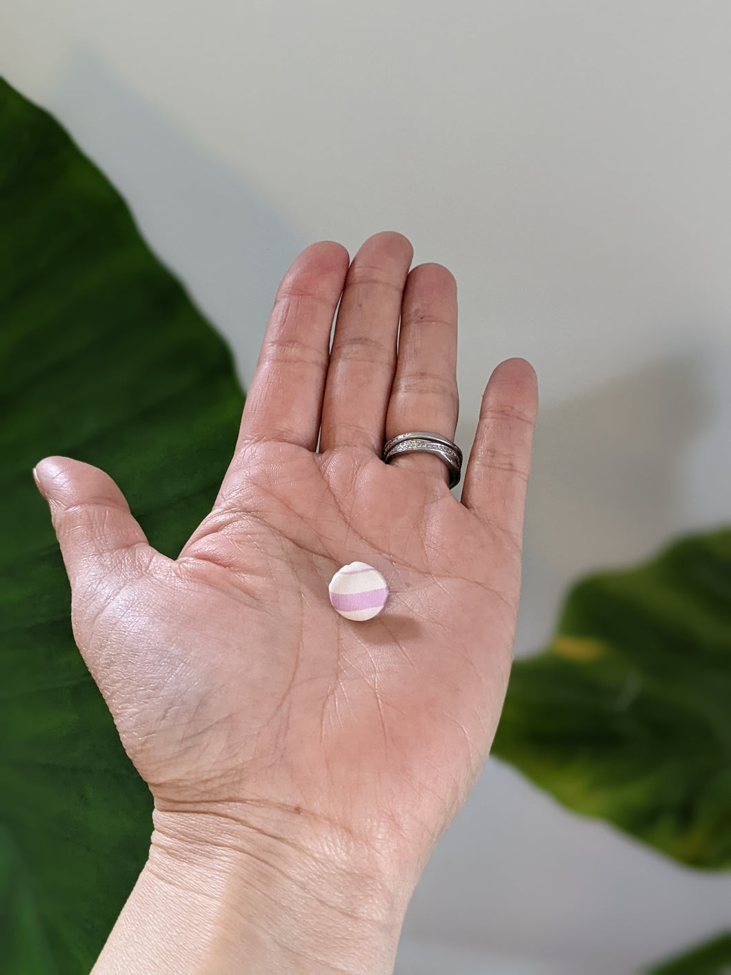 round light purple and white stripe earring on a palm